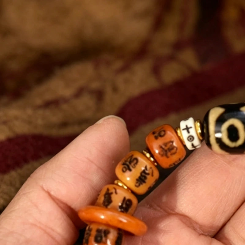Close up of Tibetan six syllable mantra Yak bone bracelet with dzi bead held in hand, vintage handmade ethnic spiritual jewelry.