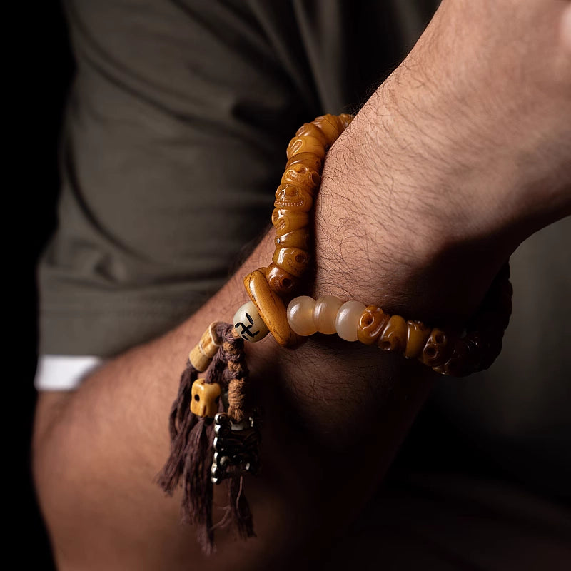 A close-up of a man wearing a chunky Tibetan yak bone bracelet on his wrist, showcasing the rugged bohemian style and hanging tassel.