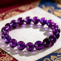 Flat lay shot of high clarity natural amethyst beaded bracelet on ornate Tibetan patterned fabric, healing quartz accessory