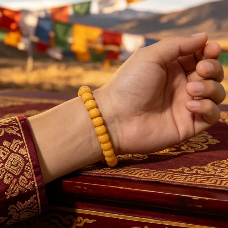 Beeswax amber bracelet worn on the wrist beside red and gold Tibetan-style brocade