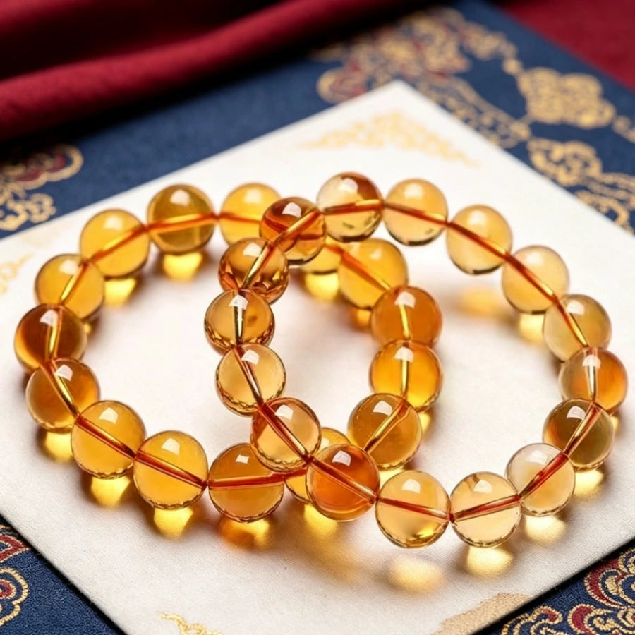 Two strands natural polished citrine quartz bead bracelet, golden translucent healing crystal jewelry laid on traditional Tibetan woven fabric
