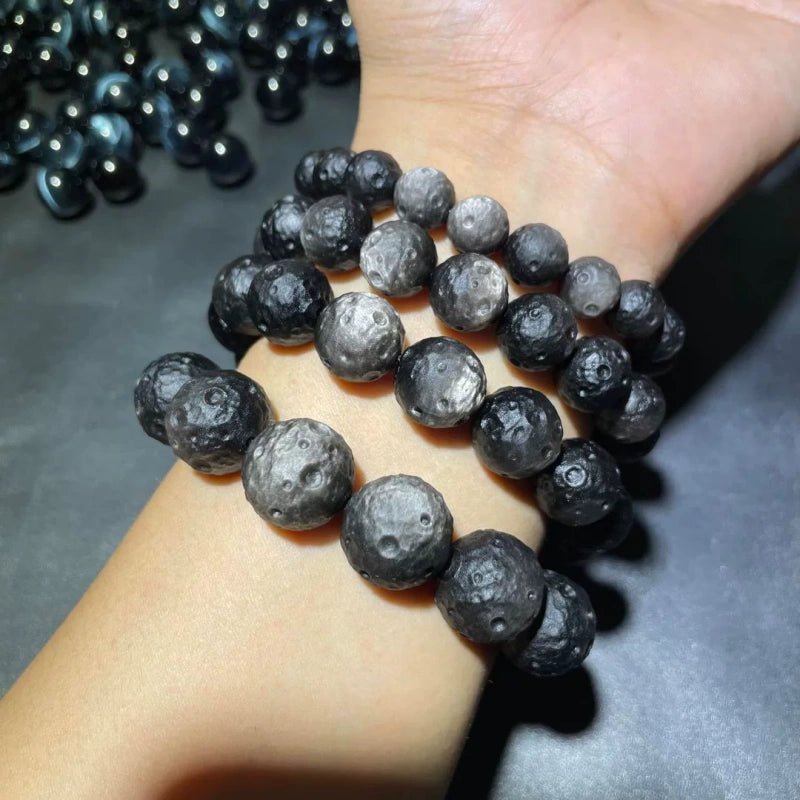 Worn shot of unisex natural obsidian bracelet with cratered lunar meteorite surface, approx 8mm textured stone beads energy healing wrist jewelry for clearing negative emotions