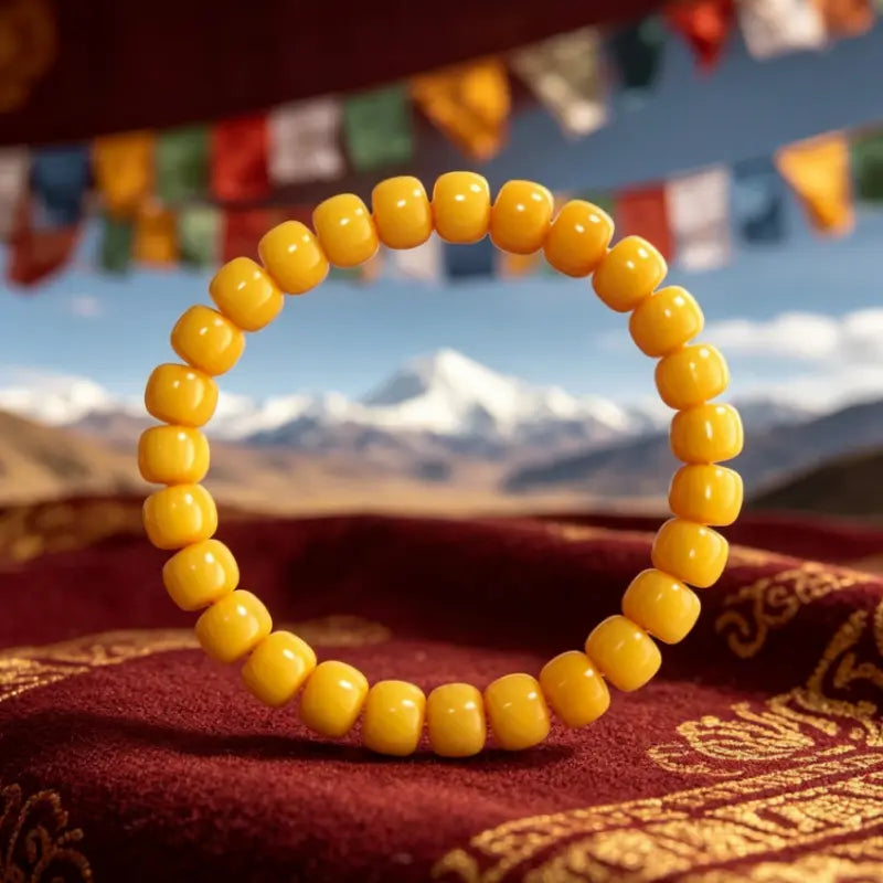 Tibetan beeswax amber bracelet with golden beads on maroon brocade with prayer flags and Himalayan mountains