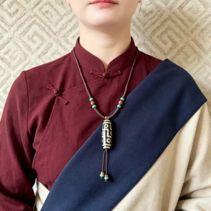 Woman wearing a Tibetan-style Dzi Bead necklace over a burgundy top with a navy sash