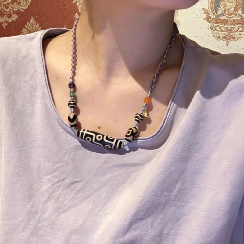 Woman wearing a Tibetan nine-eye dzi bead necklace with amethyst and agate accents