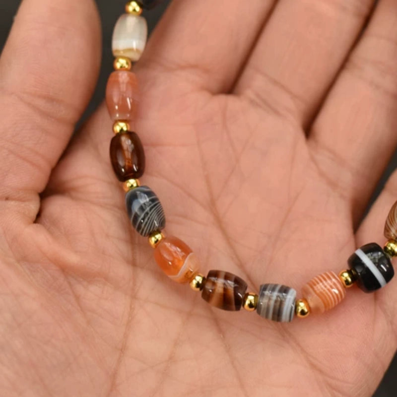 Close-up of a handcrafted Tibetan bracelet showing the unique natural striped patterns of silk agate beads and gold spacers.