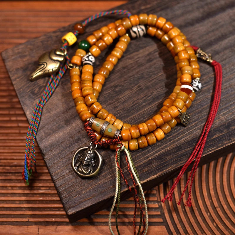 Tibetan 108 yak bone mala beads laid flat, featuring dzi bead and vintage copper details