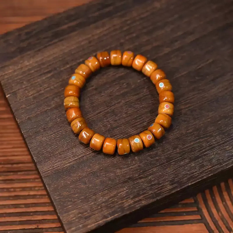 Tibetan yak bone prayer bead bracelet with turquoise and red agate accents on wood