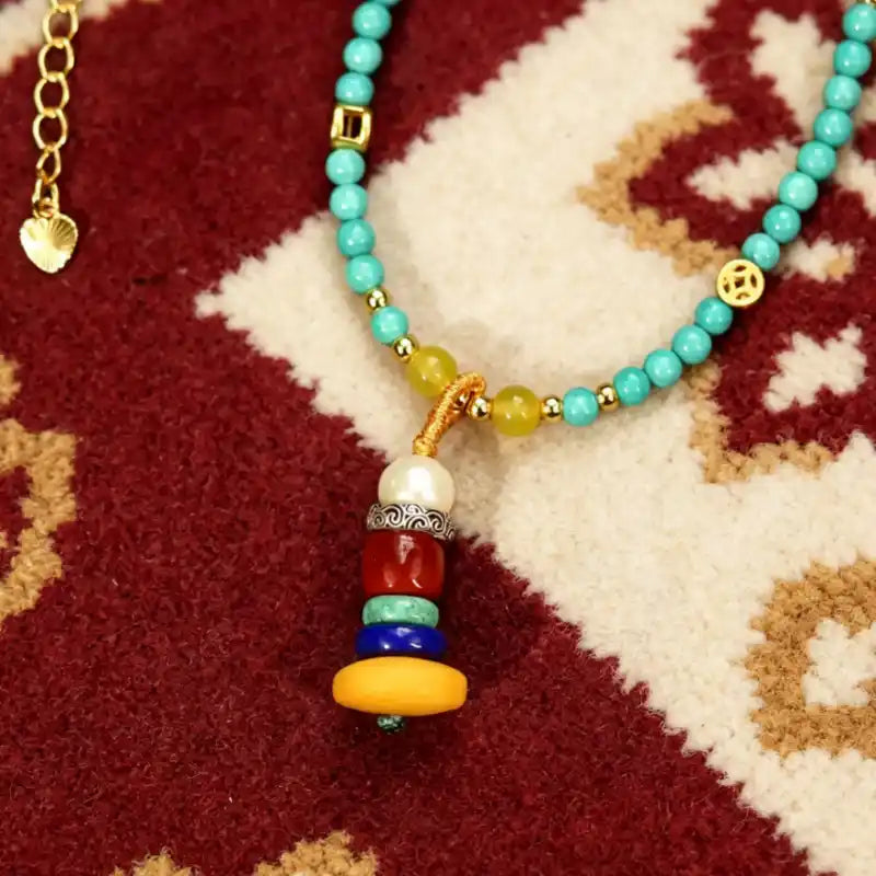 Close-up of the layered tassel pendant — pearl, red agate, lapis lazuli, and beeswax amber beads capped in Tibetan silver