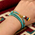Turquoise necklace wound three times around the wrist as a layered wrap bracelet, with its tassel charm hanging free