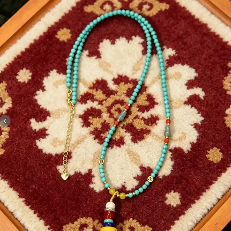 Turquoise tassel necklace laid flat, showing the gold-tone clasp and heart charm extension chain