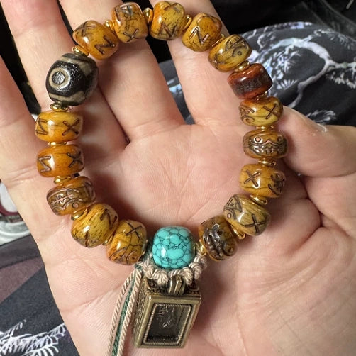 Handheld shot of retro plateau natural yak bone bracelet, featuring sky turquoise bead and portable Zhaji Lhamo gawu amulet, unisex daily meditation jewelry